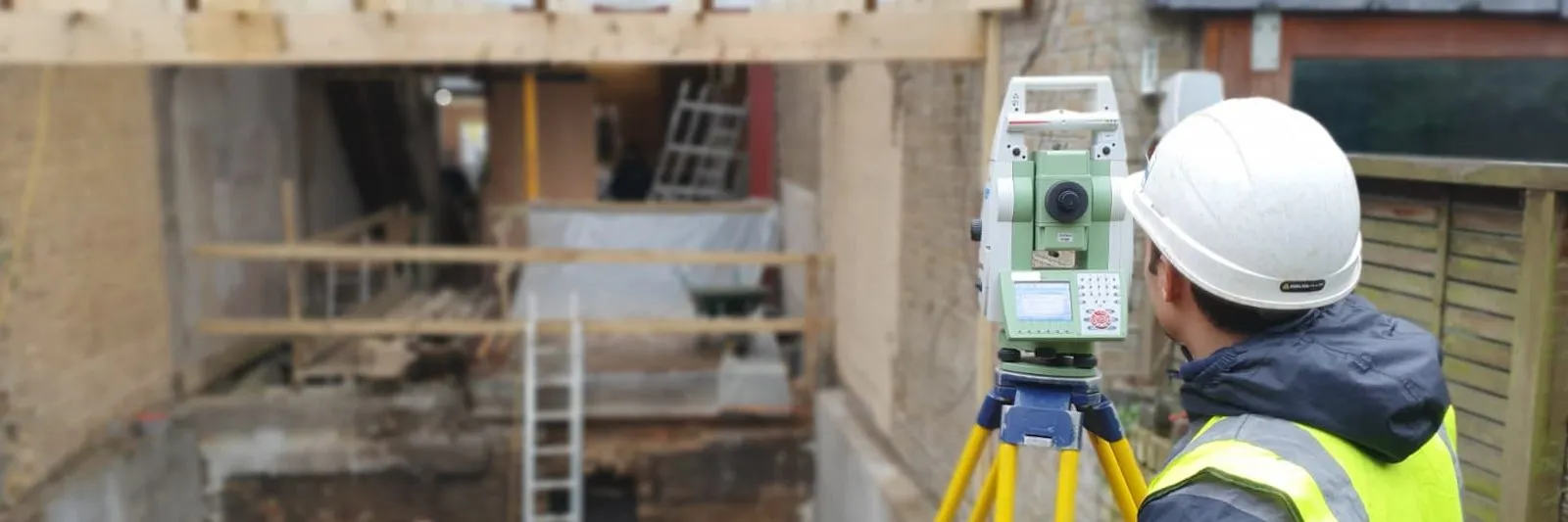 Surveyor operating a total station beside a basement excavation